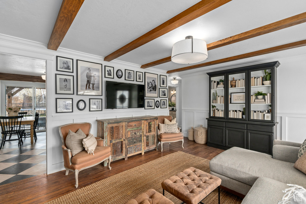 Living room featuring a decorative wall, wood finished floors, beamed ceiling, and wainscoting