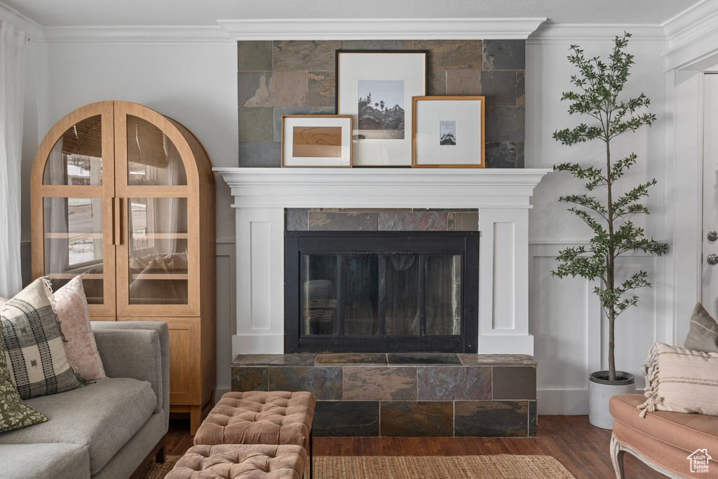 Living area with ornamental molding, wood finished floors, and a tiled fireplace