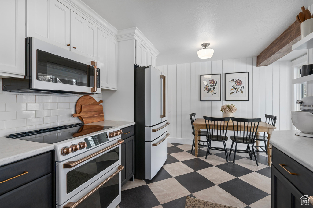 Kitchen with white cabinetry, light countertops, tasteful backsplash, white appliances, and light floors