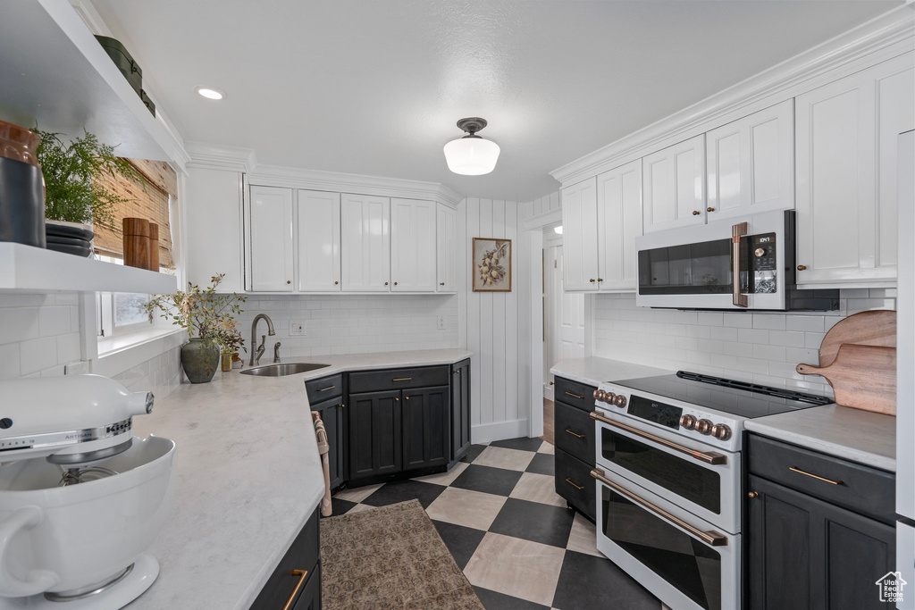 Kitchen with light countertops, white appliances, dark floors, a sink, and white cabinets
