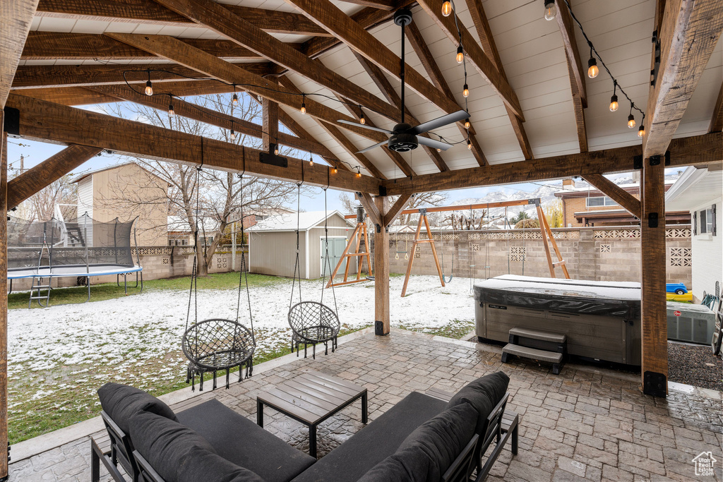View of patio / terrace with a trampoline, an outdoor structure, a storage shed, a hot tub, and an outdoor hangout area