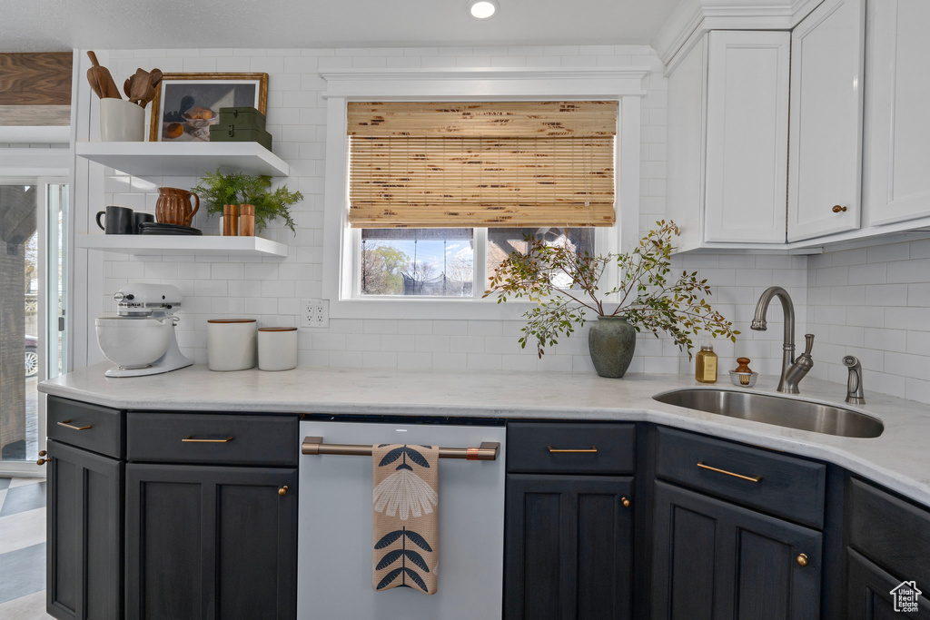 Kitchen with backsplash, open shelves, a sink, dishwasher, and white cabinets