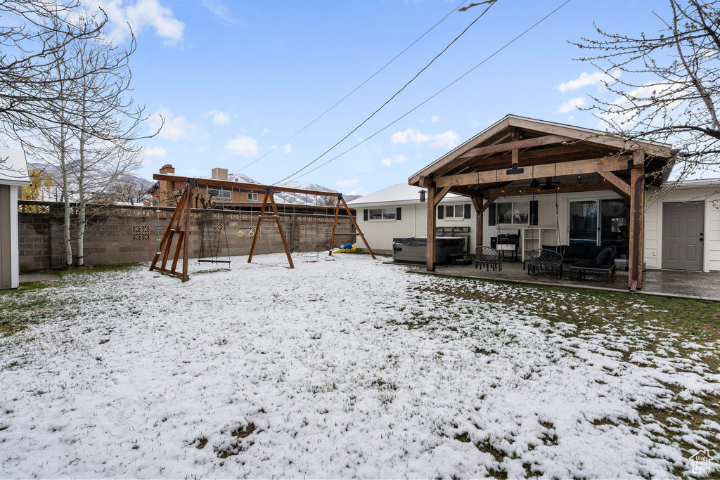 Yard covered in snow with a patio, ceiling fan, a fenced backyard, and a playground