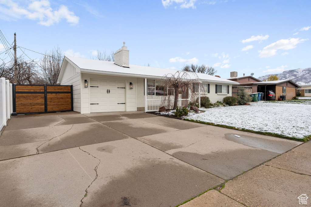 Ranch-style house with an attached garage, a chimney, fence, and driveway