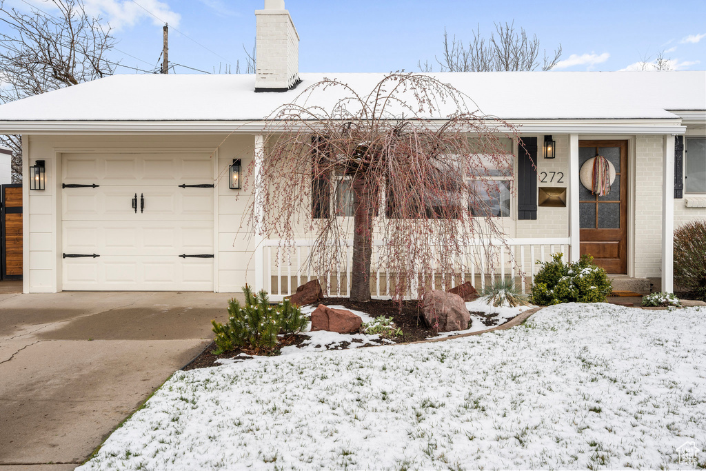 Single story home featuring driveway, an attached garage, a chimney, and brick siding