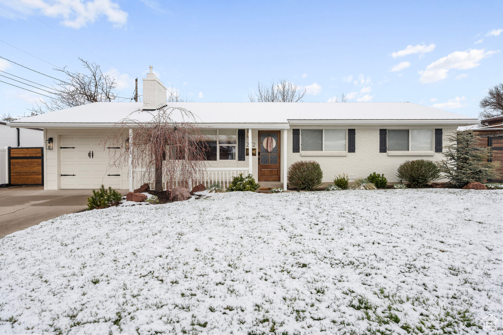 Ranch-style home featuring a chimney, brick siding, driveway, and an attached garage