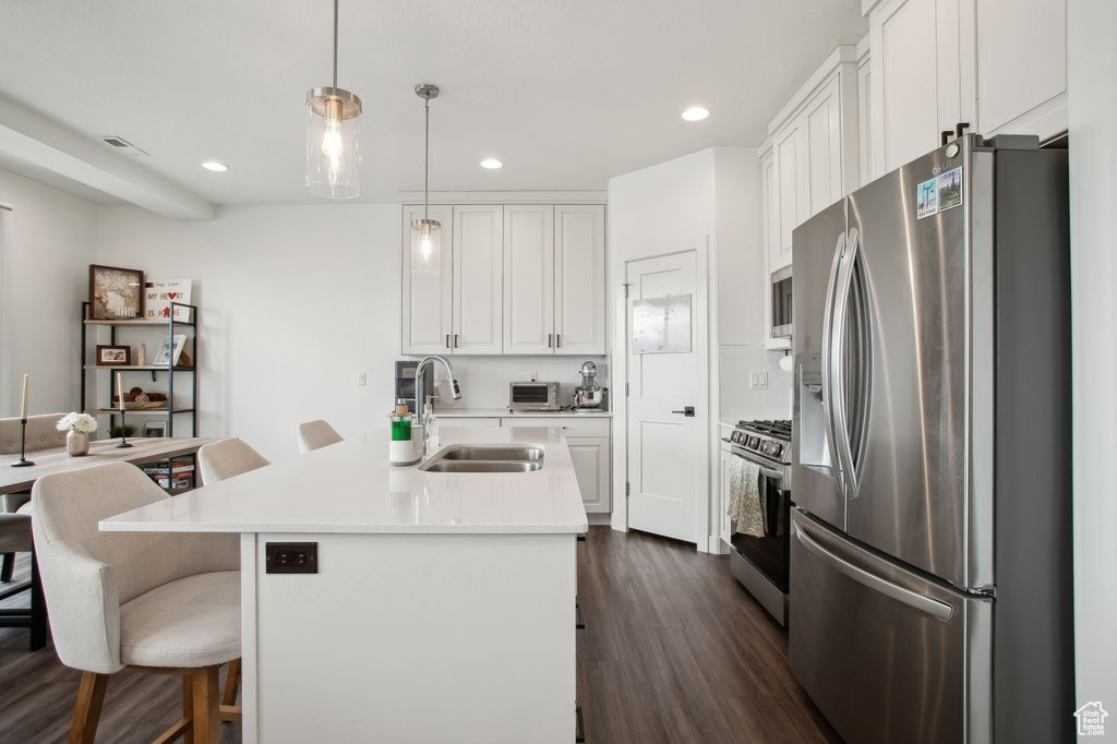 Kitchen with visible vents, white cabinets, a sink, and stainless steel appliances