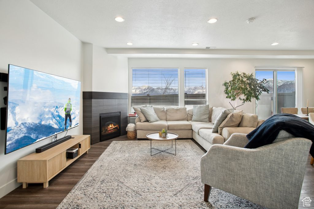 Living room featuring recessed lighting, a textured ceiling, dark wood finished floors, visible vents, and a fireplace