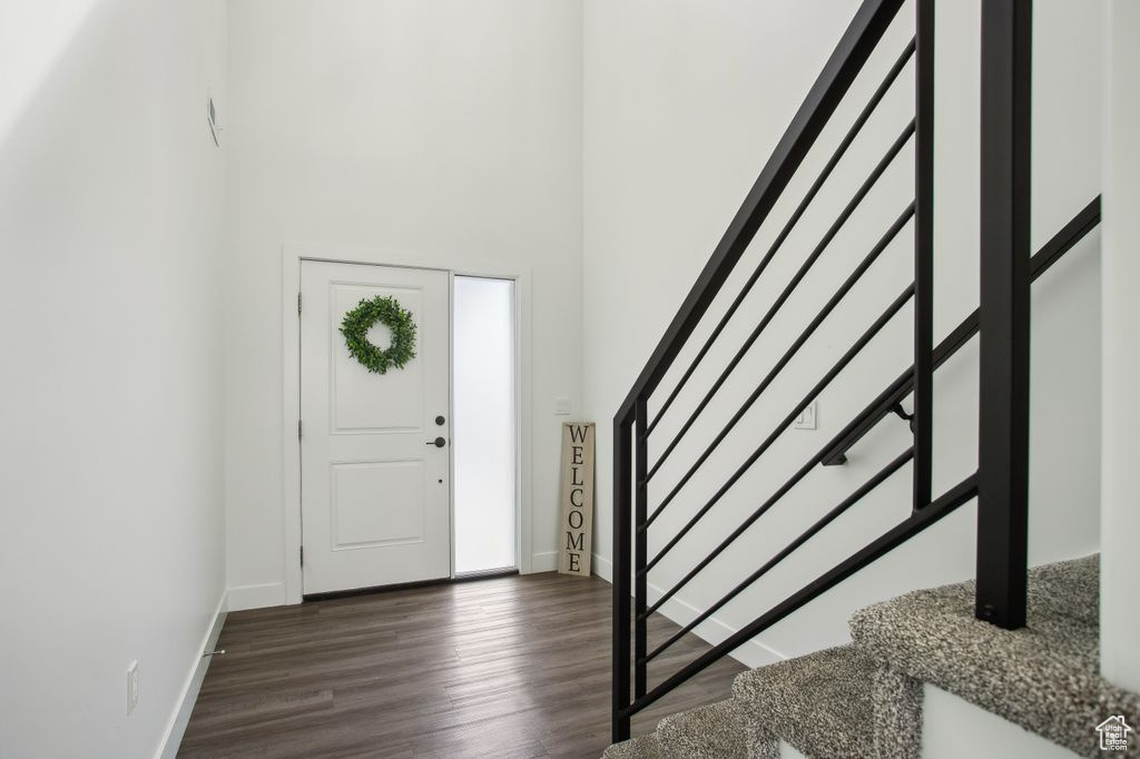 Foyer featuring baseboards, dark wood-style floors, and stairway