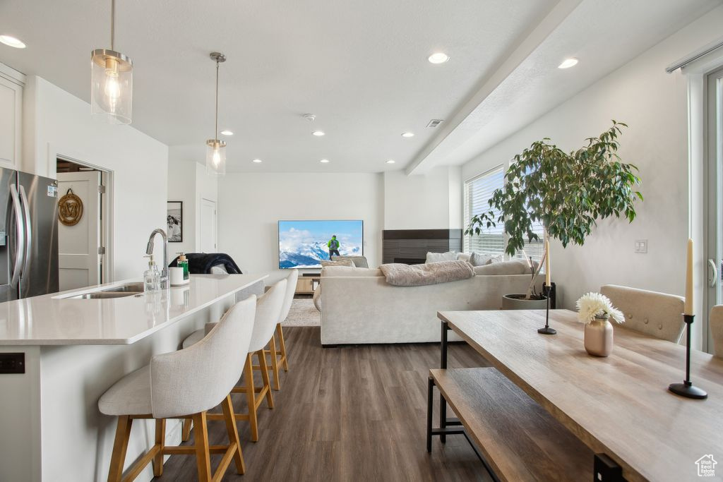Kitchen with recessed lighting, dark wood-style floors, a sink, a breakfast bar area, and freestanding refrigerator