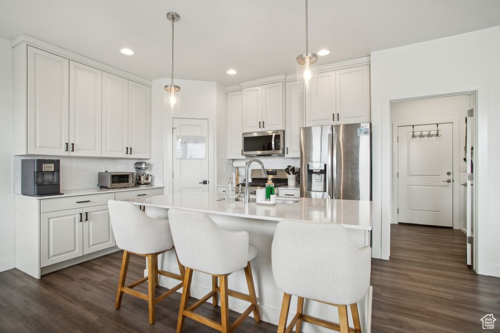Kitchen with dark wood-style floors, white cabinets, appliances with stainless steel finishes, and a sink