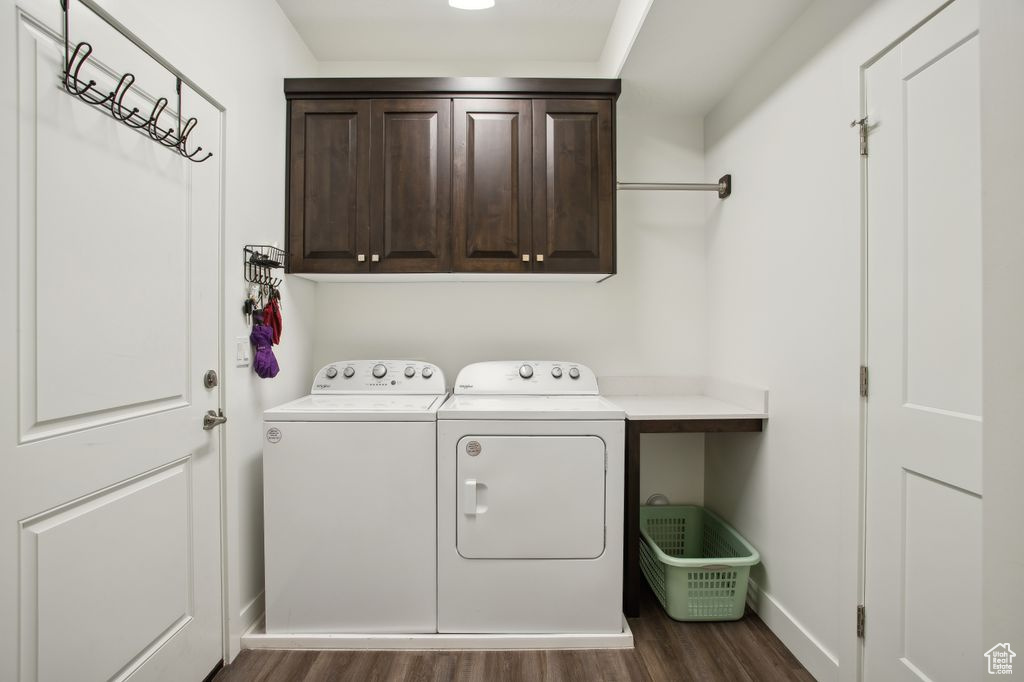 Laundry area with dark wood-type flooring, cabinet space, baseboards, and washer and dryer