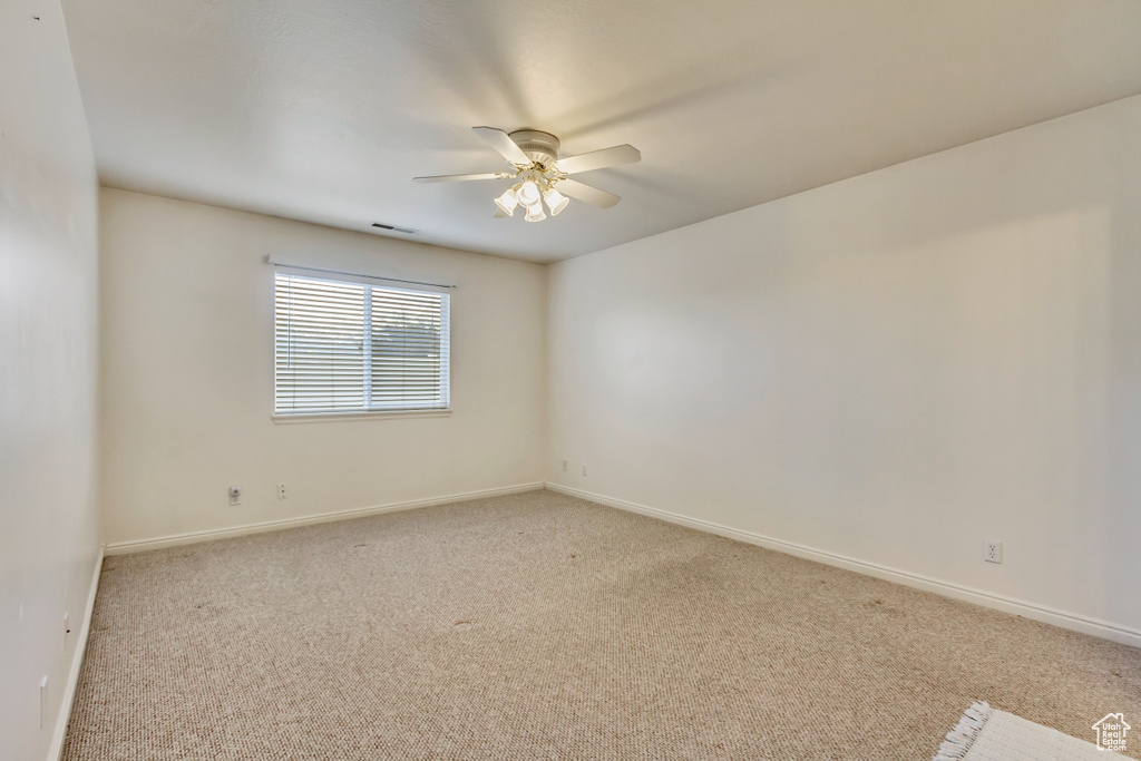 Unfurnished room with baseboards, visible vents, a ceiling fan, and light carpet