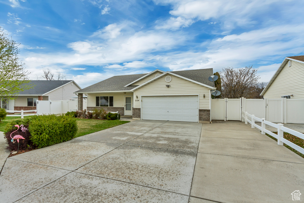 View of front of house featuring a gate, fence, a garage, concrete driveway, and brick siding