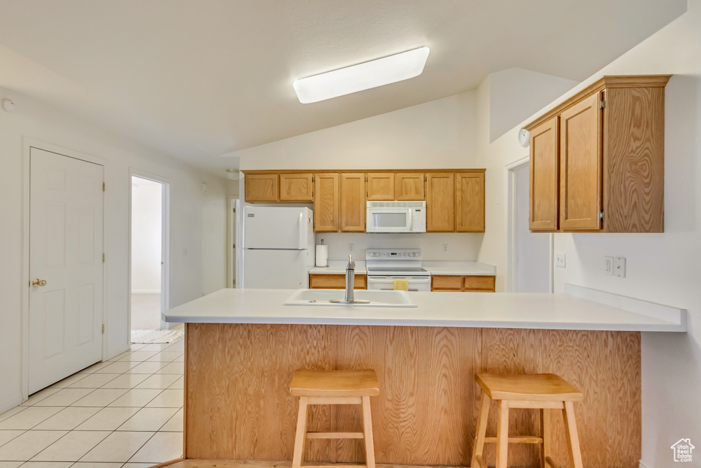Kitchen with light countertops, a sink, light tile patterned floors, and white appliances