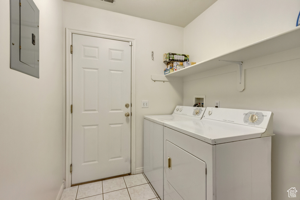 Washroom with electric panel, light tile patterned flooring, washing machine and clothes dryer, and laundry area