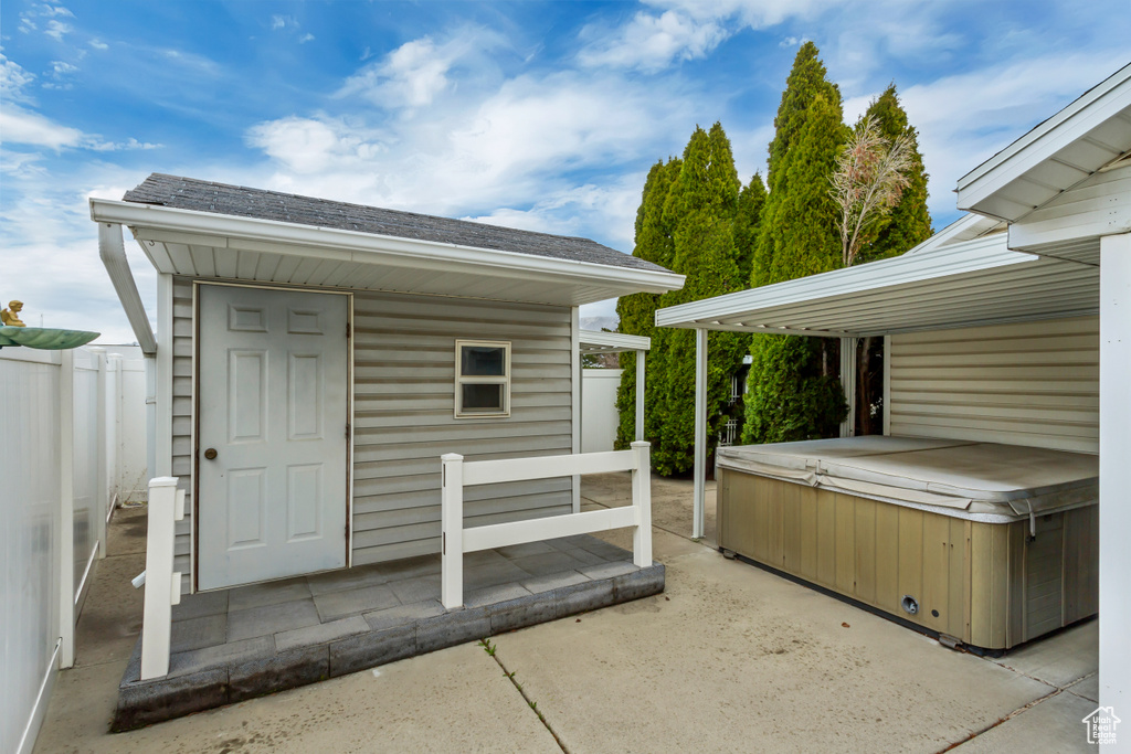 View of outdoor structure with an outdoor structure, fence, and a hot tub