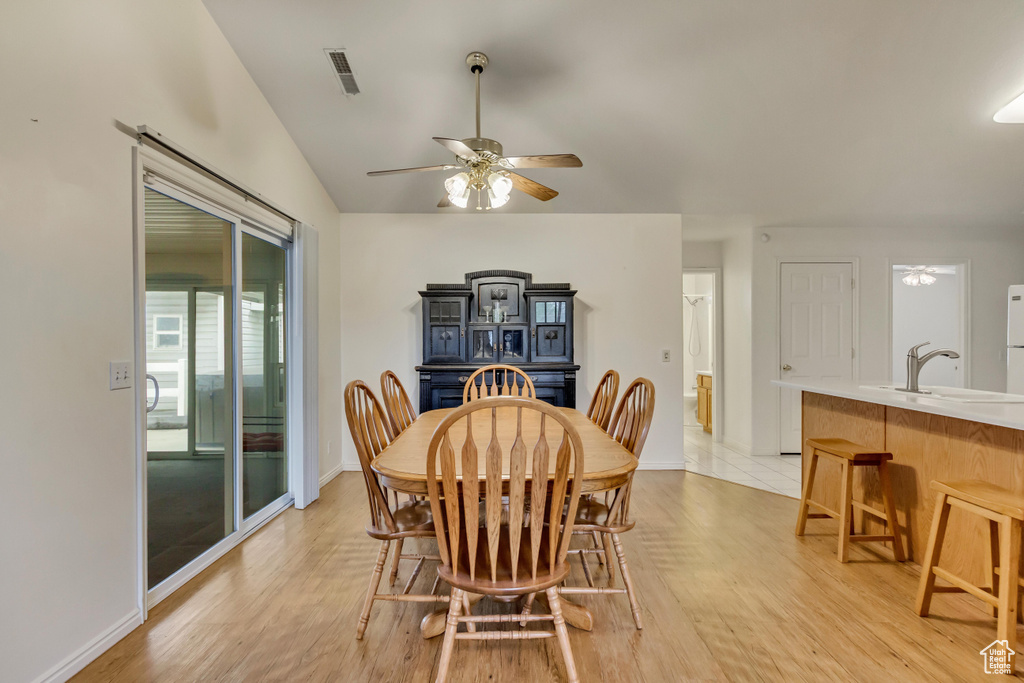 Dining room with visible vents, ceiling fan, light wood-style flooring, and vaulted ceiling