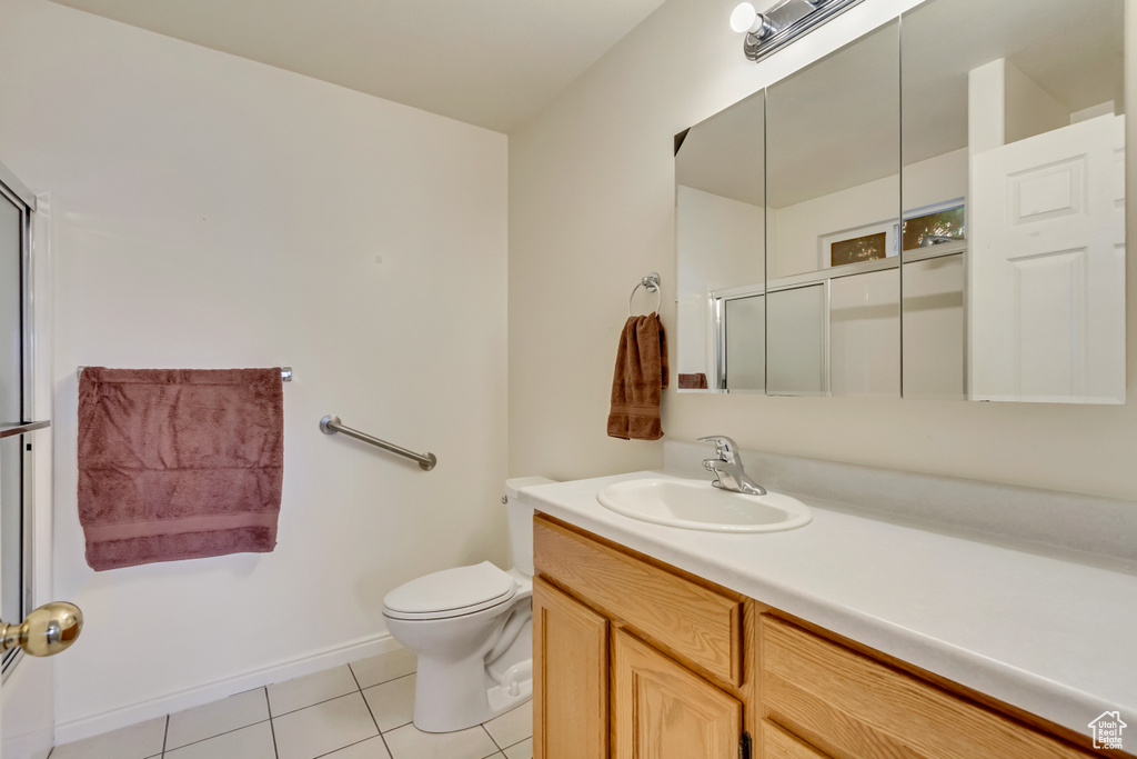 Bathroom featuring baseboards, toilet, vanity, an enclosed shower, and tile patterned flooring