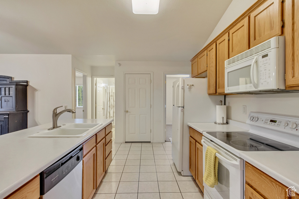 Kitchen featuring light tile patterned flooring, white appliances, light countertops, and a sink
