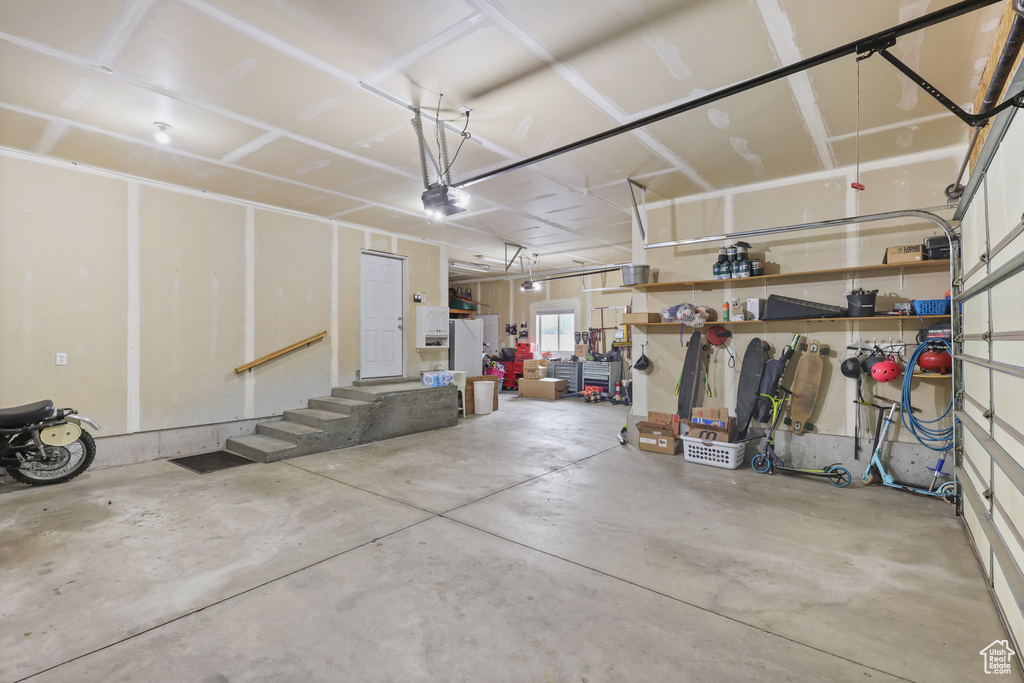 Garage with freestanding refrigerator and a garage door opener