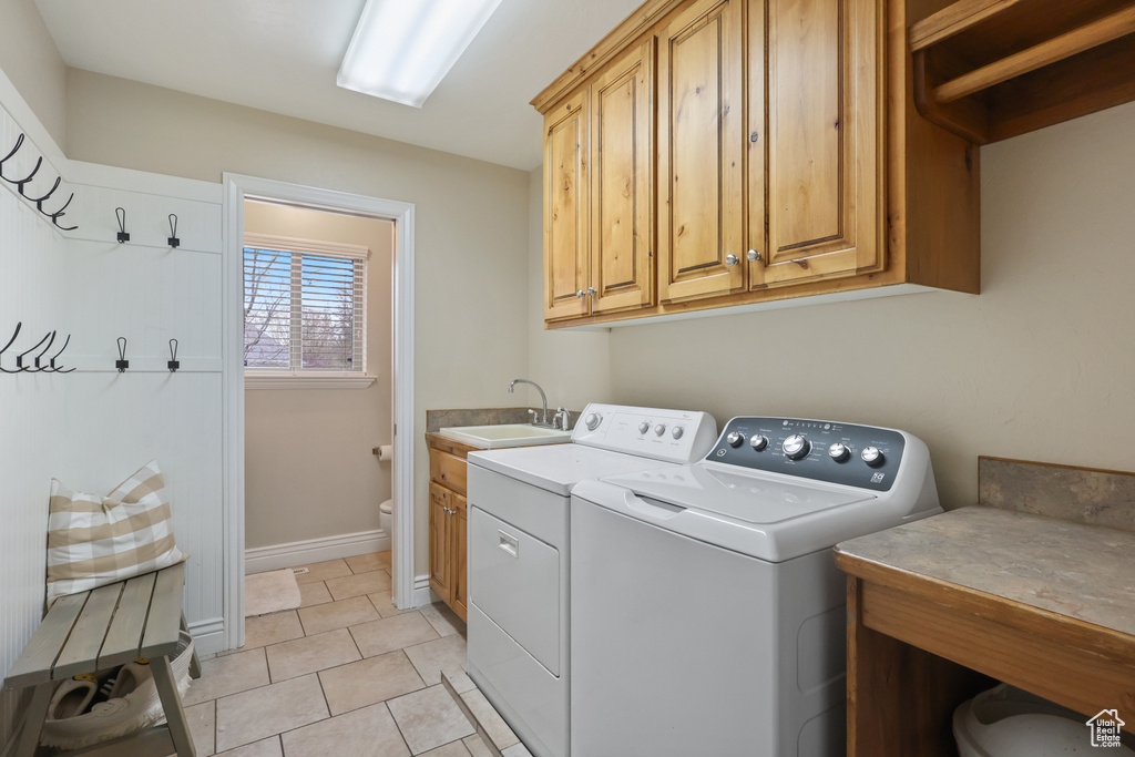Laundry room with baseboards, a sink, washer and clothes dryer, cabinet space, and light tile patterned floors