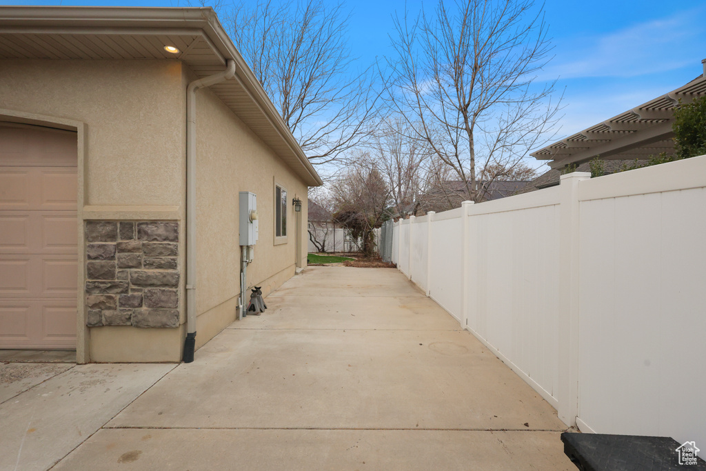 View of home's exterior with stucco siding, fence, and a patio