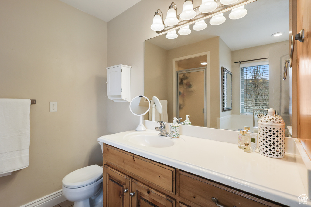 Full bath featuring a stall shower, toilet, vanity, a baseboard radiator, and baseboards