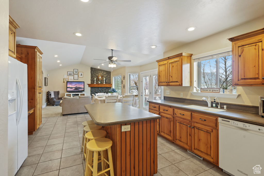 Kitchen with white appliances, a kitchen island, a ceiling fan, a sink, and open floor plan