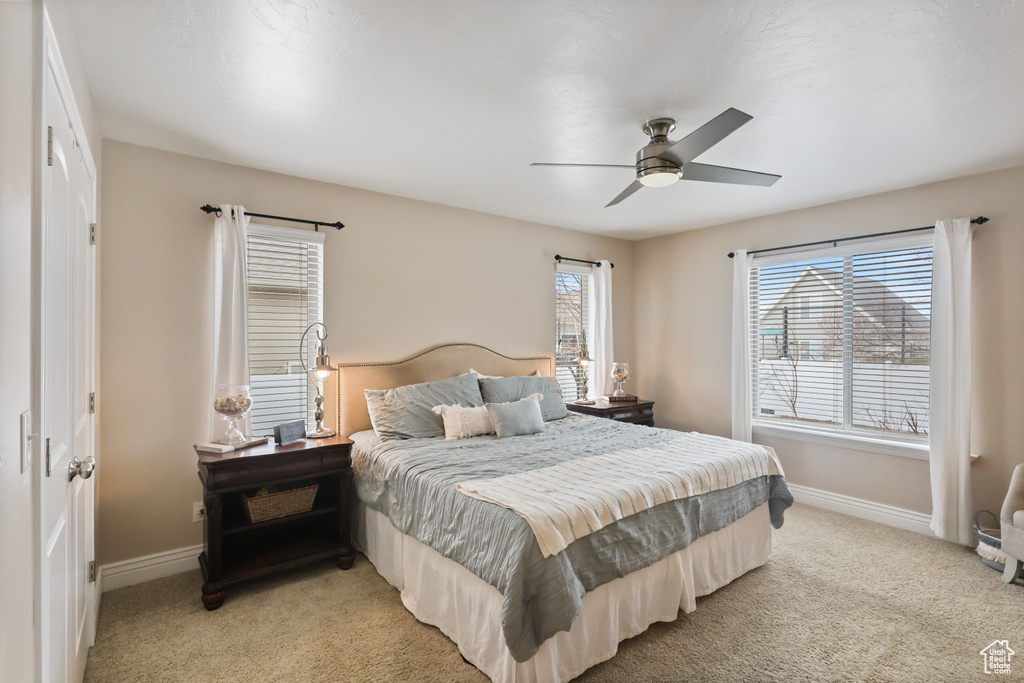 Bedroom featuring light carpet, baseboards, and ceiling fan