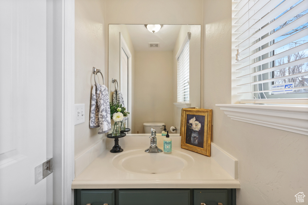Bathroom featuring visible vents, toilet, and vanity