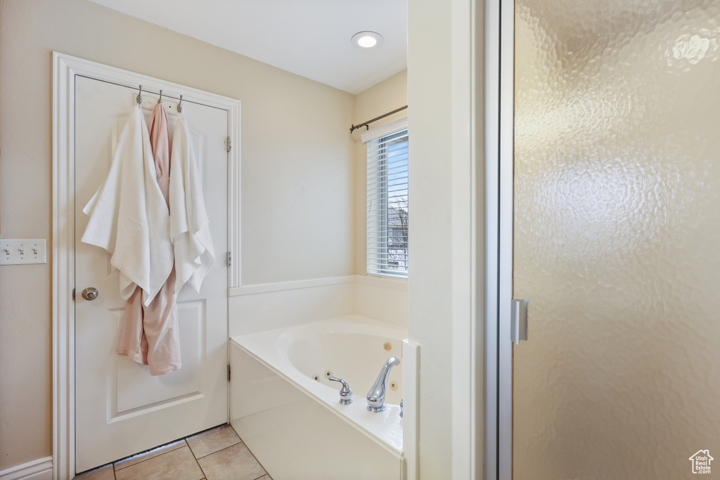 Bathroom with a tub with jets, tile patterned floors, and a stall shower