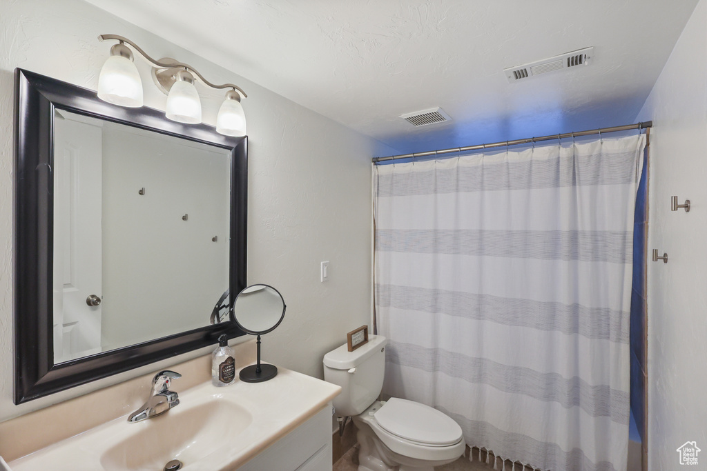 Bathroom featuring curtained shower, visible vents, toilet, and vanity