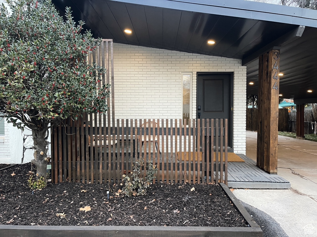 View of exterior entry with fence and brick siding