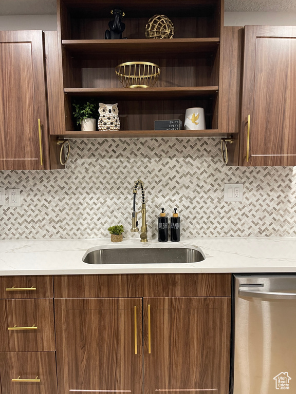 Kitchen with stainless steel dishwasher, backsplash, a sink, and open shelves