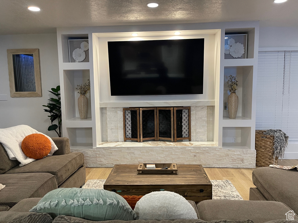 Living room with a textured ceiling, wood finished floors, and built in shelves