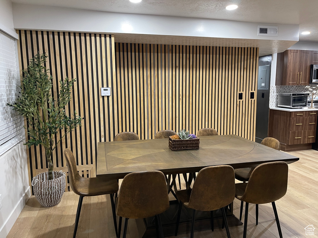 Dining room with recessed lighting, a textured ceiling, a toaster, light wood finished floors, and visible vents