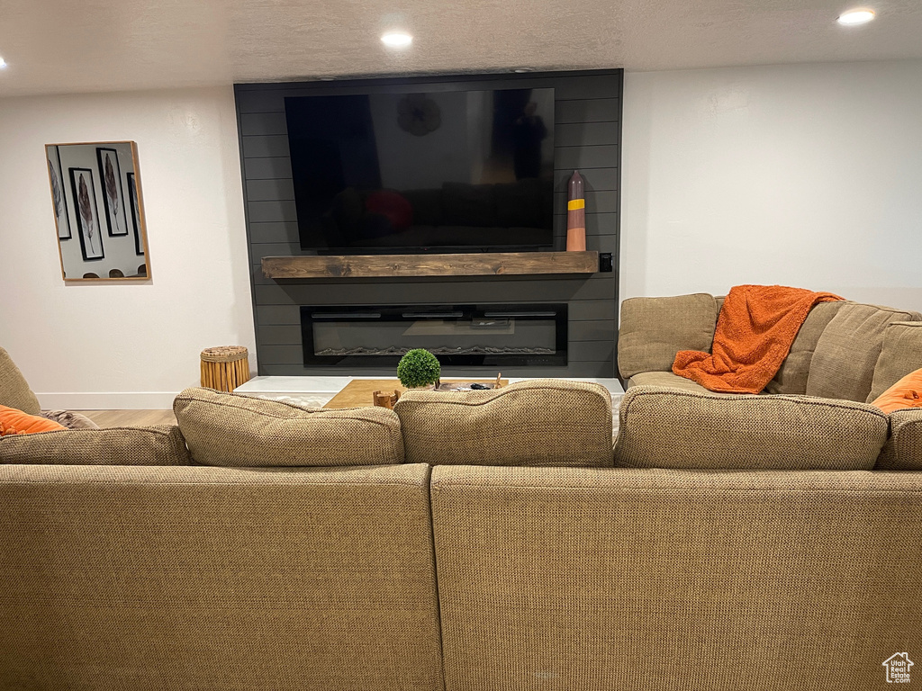 Living room featuring recessed lighting, baseboards, a fireplace, and wood finished floors