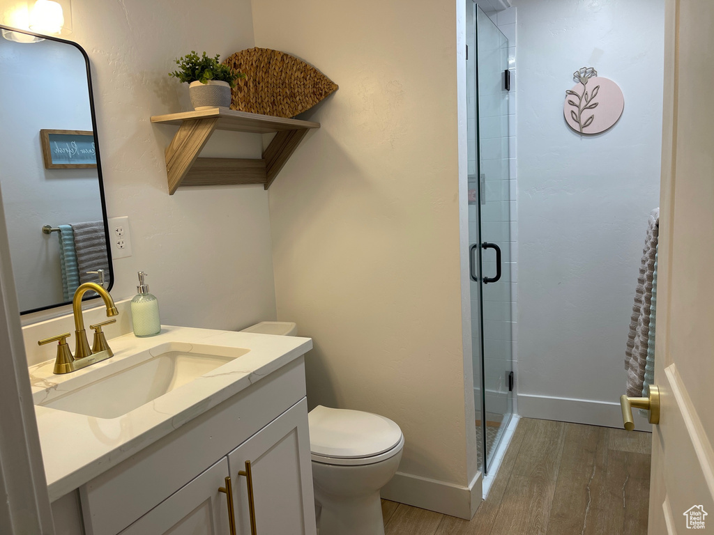 Full bath with baseboards, wood finished floors, toilet, vanity, and a stall shower