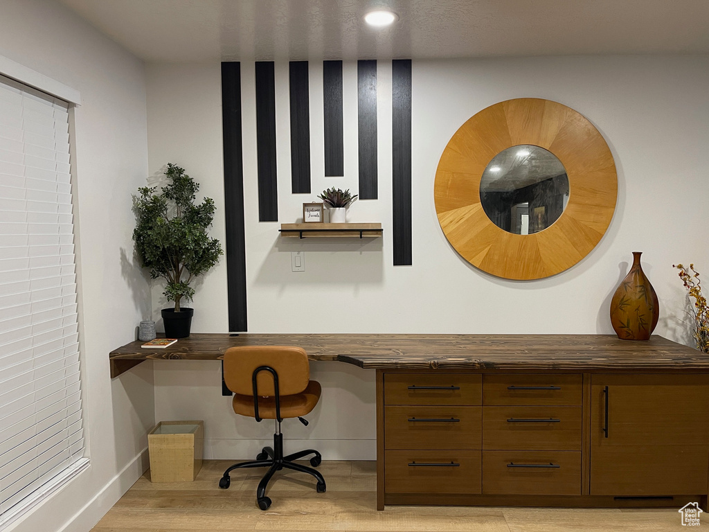 Home office featuring baseboards, built in desk, and light wood-style flooring