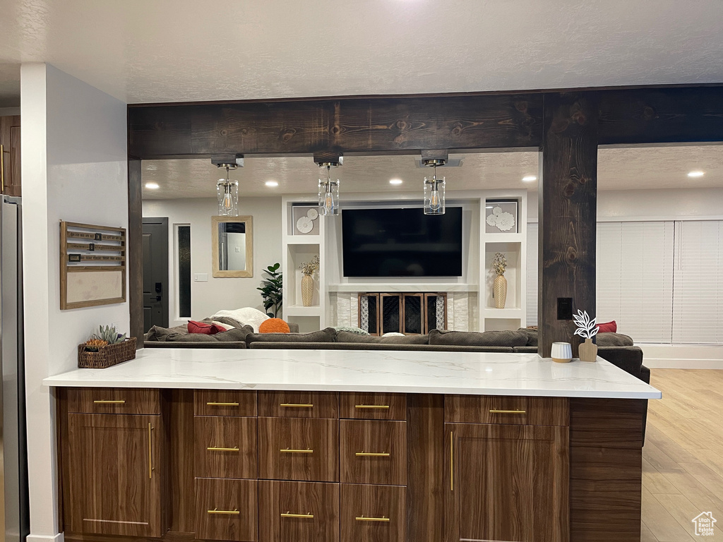 Kitchen with open floor plan, pendant lighting, light stone countertops, and light wood finished floors