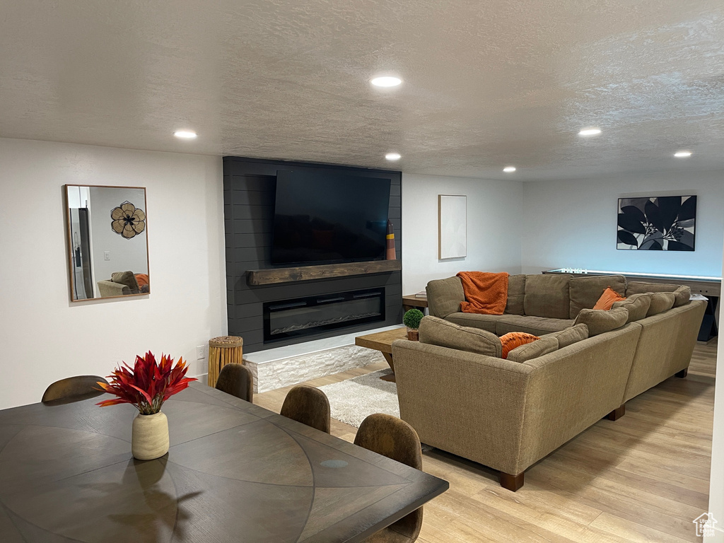 Living area featuring a textured ceiling, a fireplace, recessed lighting, and light wood-style floors