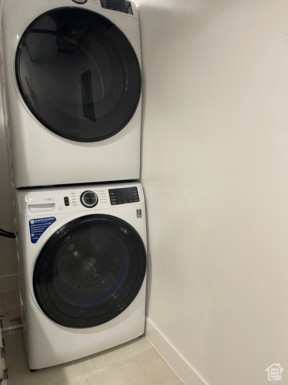Laundry area with baseboards, stacked washer / drying machine, laundry area, and tile patterned flooring