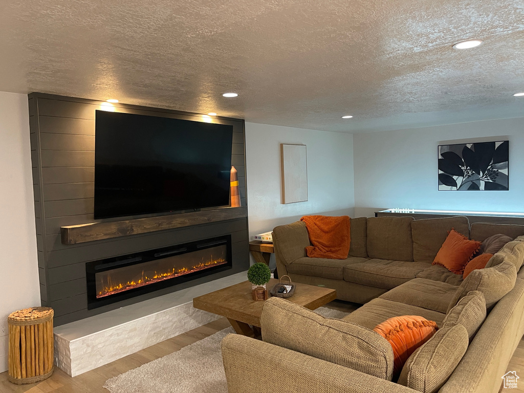 Living room featuring a fireplace, wood finished floors, recessed lighting, and a textured ceiling