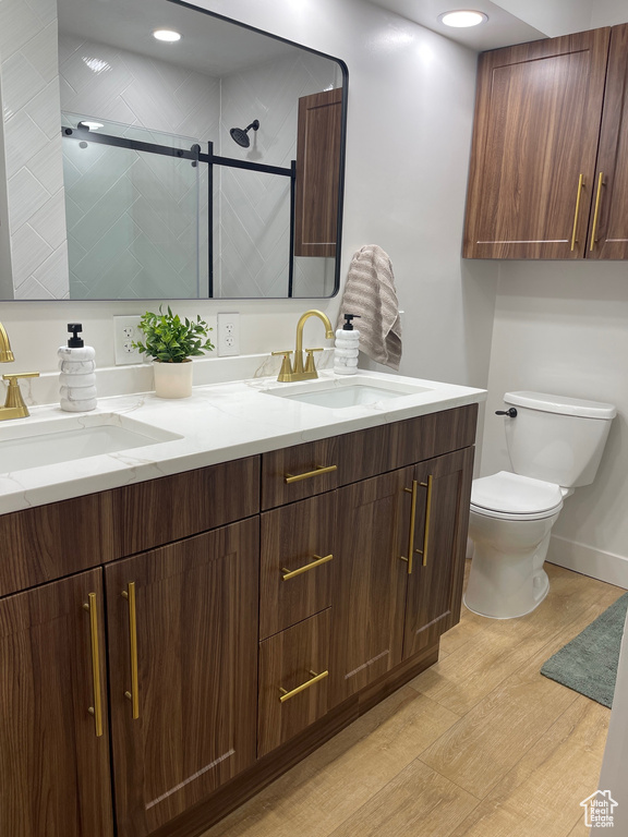 Bathroom with toilet, a sink, a stall shower, and wood finished floors