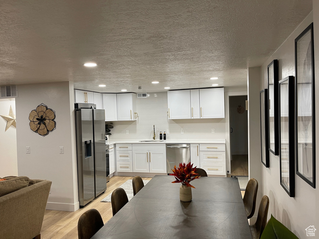 Dining space featuring a textured ceiling, visible vents, recessed lighting, and light wood-type flooring