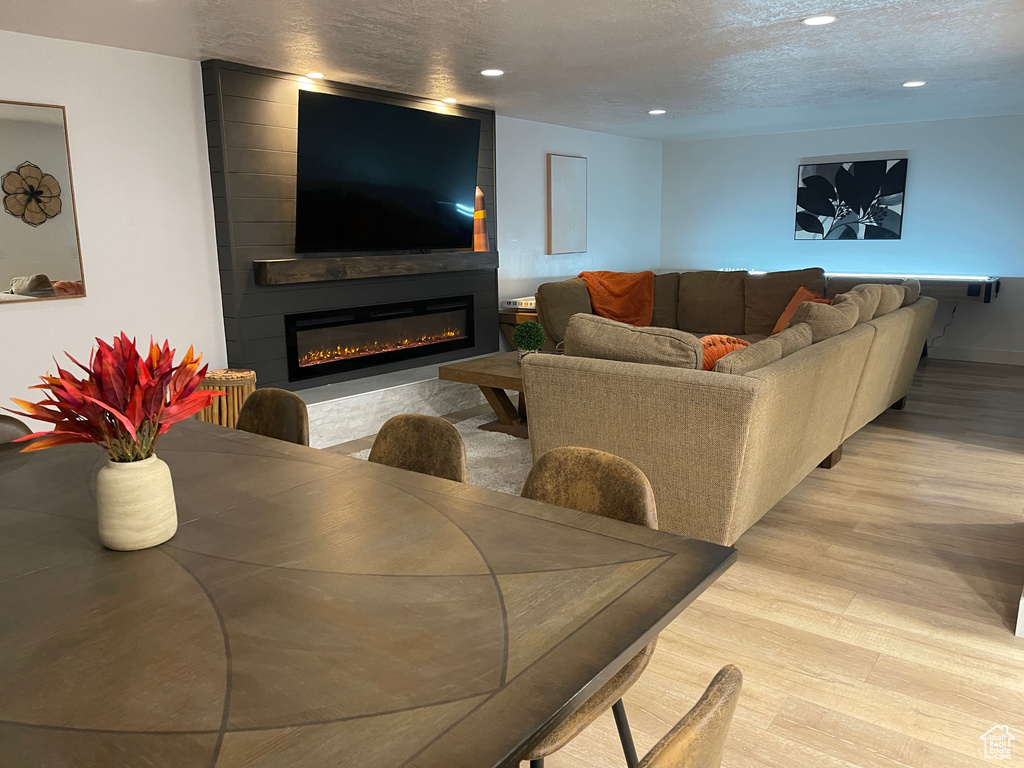 Living room with light wood finished floors, a fireplace, recessed lighting, and a textured ceiling