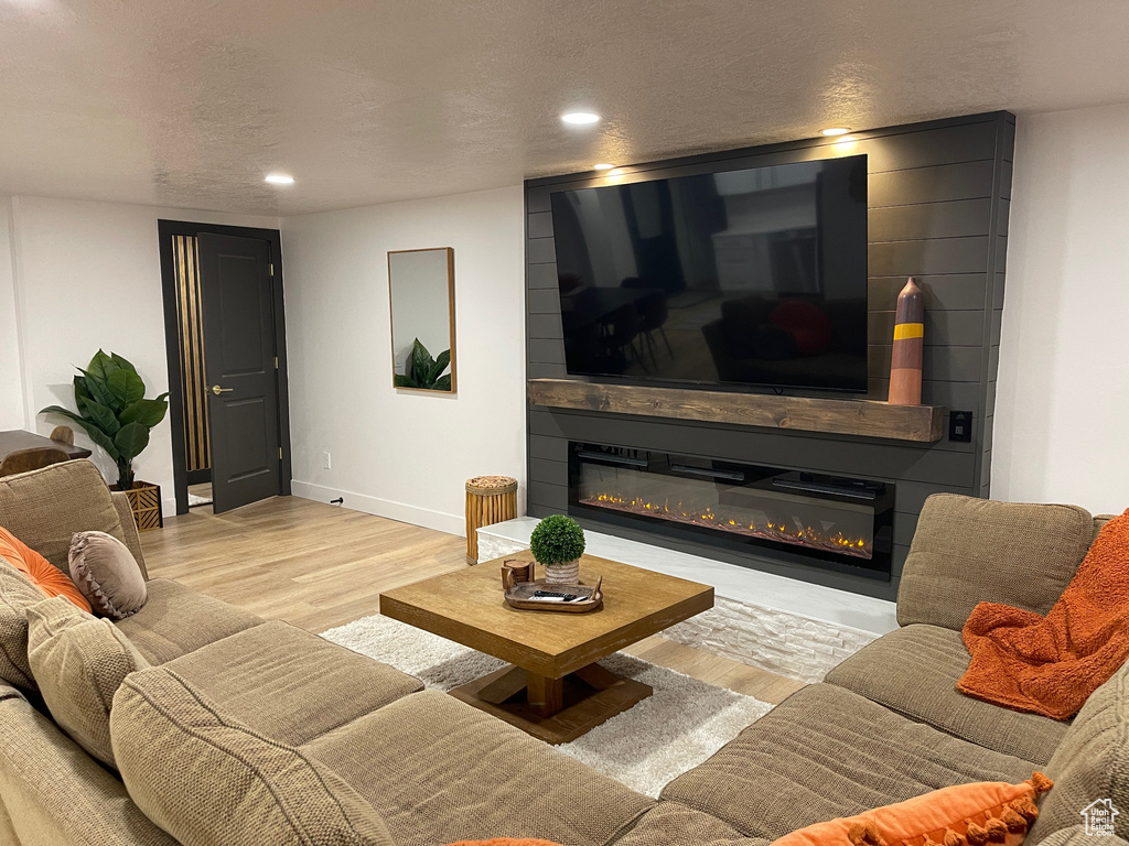 Living room featuring recessed lighting, baseboards, a fireplace, and wood finished floors