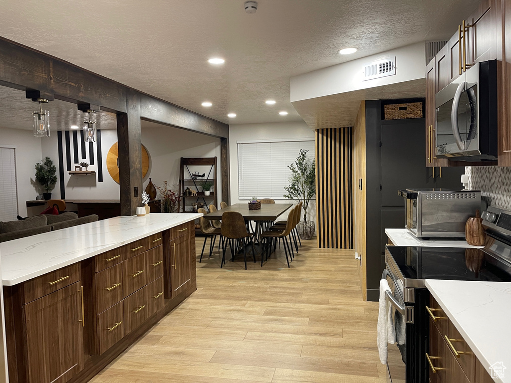 Kitchen with light wood finished floors, a textured ceiling, stainless steel appliances, visible vents, and recessed lighting