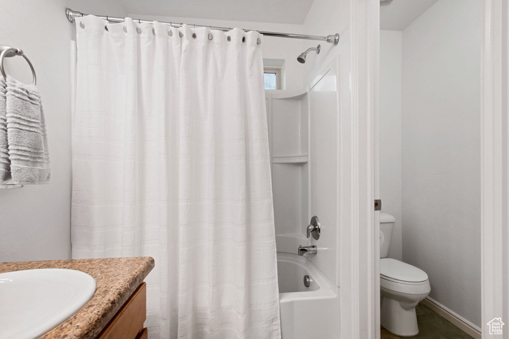 Bathroom featuring toilet, shower / bath combo with shower curtain, and vanity
